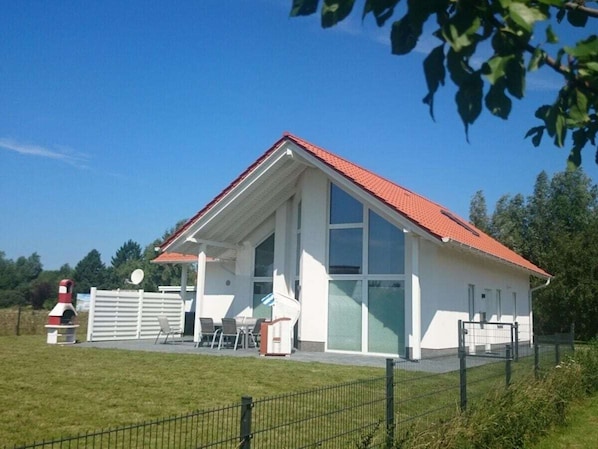 A white building with a red roof, large windows, and a fenced outdoor area with chairs. - "captain Dornfelder" (Trent)