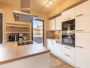A modern kitchen with wooden cabinetry, stainless steel appliances, and a view of a wooden deck outside. - Cabin With 1 Bedroom (Sankt Georgen am Kreischberg)