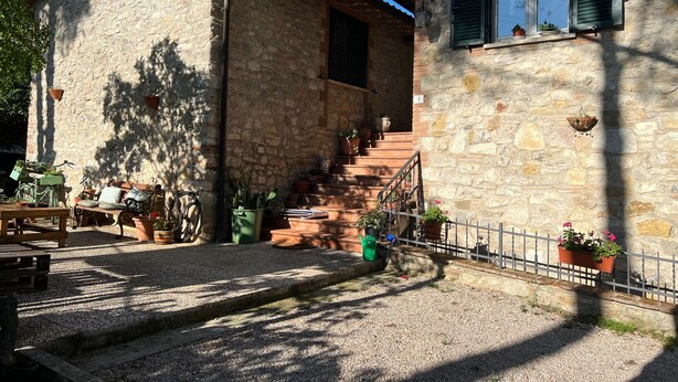 A stone building with a staircase leading to a second floor, surrounded by gravel and potted plants. - B&B La Locanda delle Idee Perugia – Apartment in a stone farmhouse (Umbria)