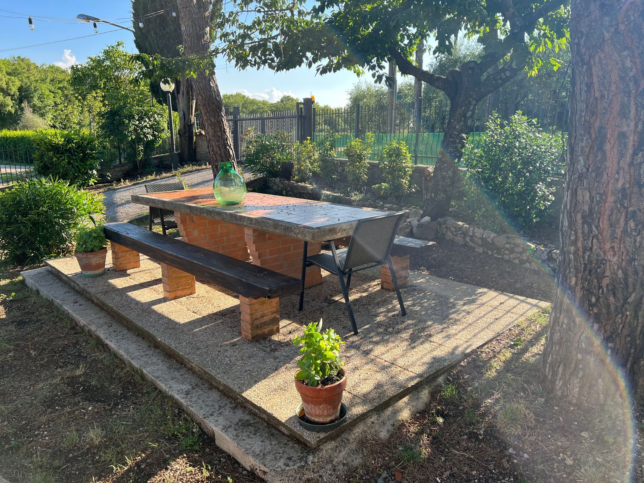 Ein Außenbereich mit einer Terrasse, einem Ziegeltisch, Bänken und einem Blumentopf.