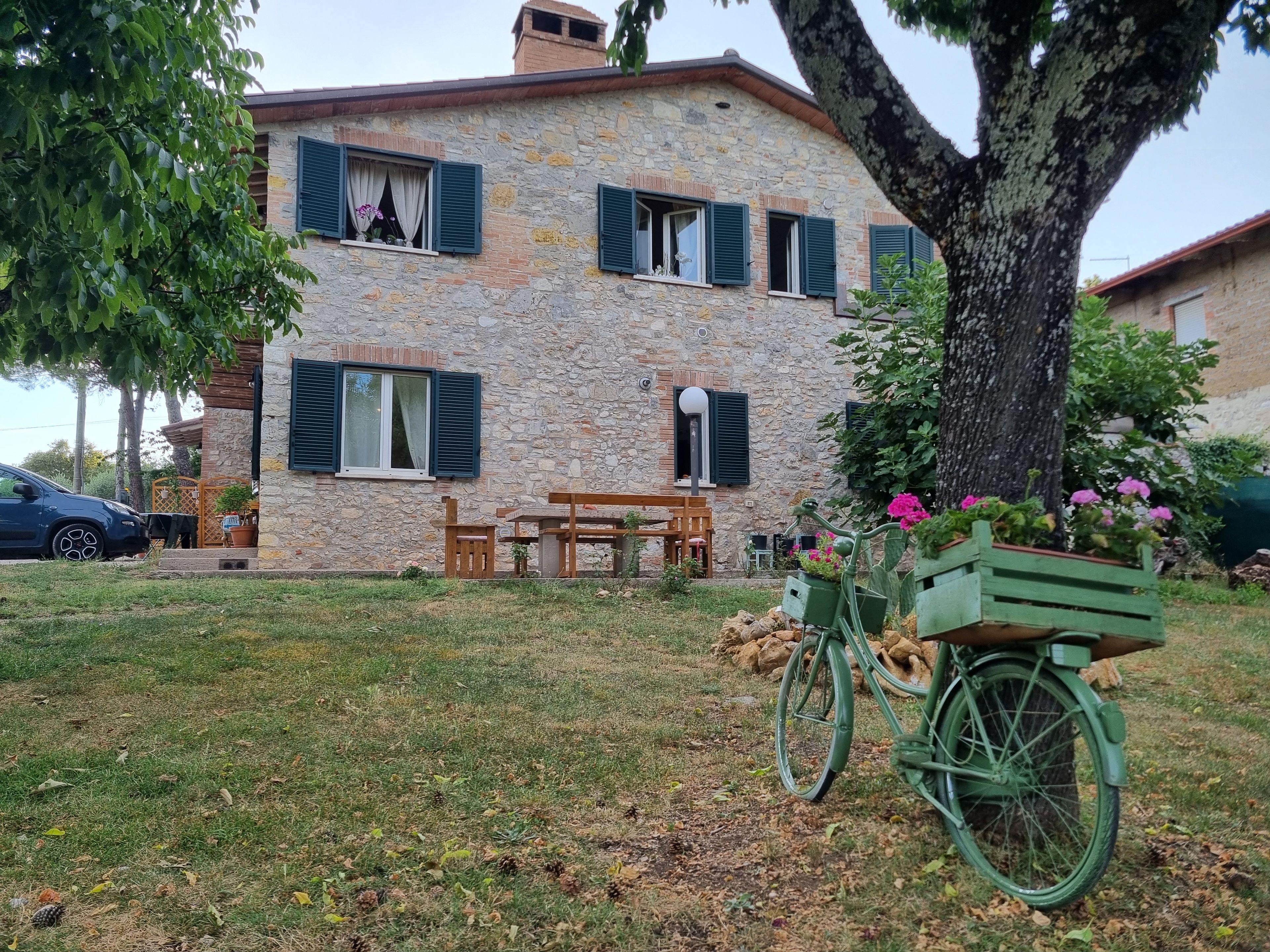 Una casa in pietra con un patio, una bicicletta e un'auto parcheggiate davanti.