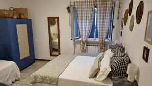A bedroom with a bed, a blue wardrobe, a mirror, a window with curtains, and a radiator. - B&B La Locanda delle Idee Perugia – Apartment in a stone farmhouse (Umbria)