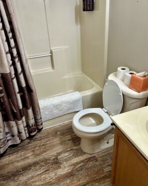 Et badeværelse med toilet, bruser og badekar.