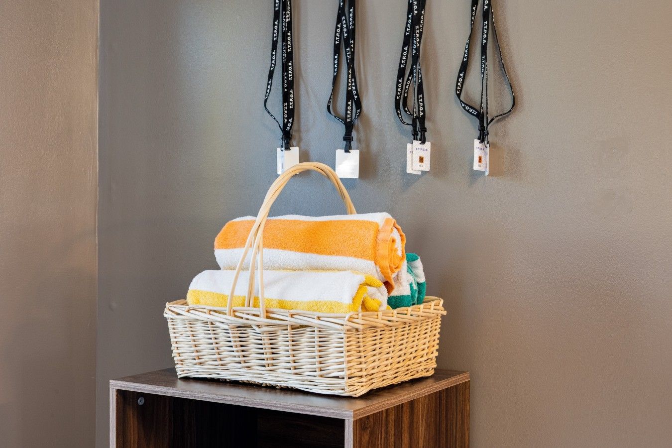 A wicker basket with towels and toiletries on a wooden stool.