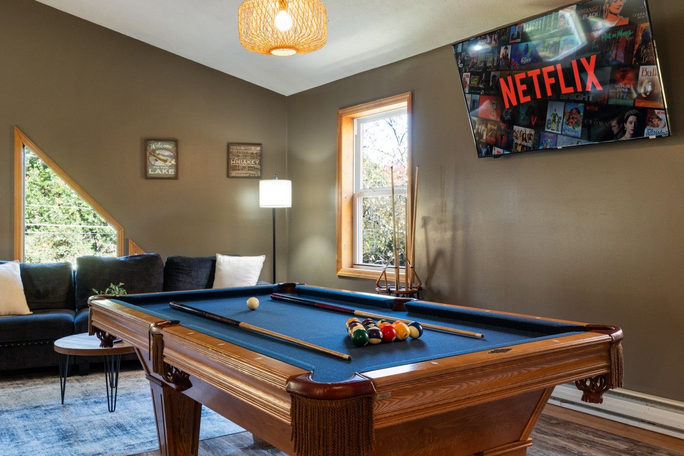 Biljardipöytä biljardipalloineen, sohva, lamppu ja seinälle asennettu televisio, jossa näkyy Netflixin käyttöliittymä.