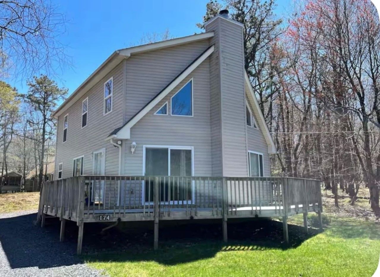 A two-story house with a deck, a chimney, and a fenced yard.