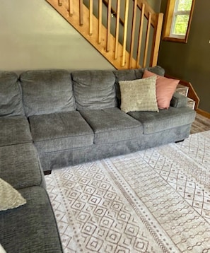 Ein graues Sofa mit gemusterten Zierkissen und einem geometrischen Teppich.