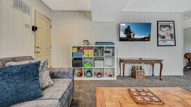 A living room with a sofa, a coffee table, a bookshelf, a television, and a poster on the wall. - Walk 2 Ski: Groups, Kids, Spacious & Well-Stocked (Lake Harmony)