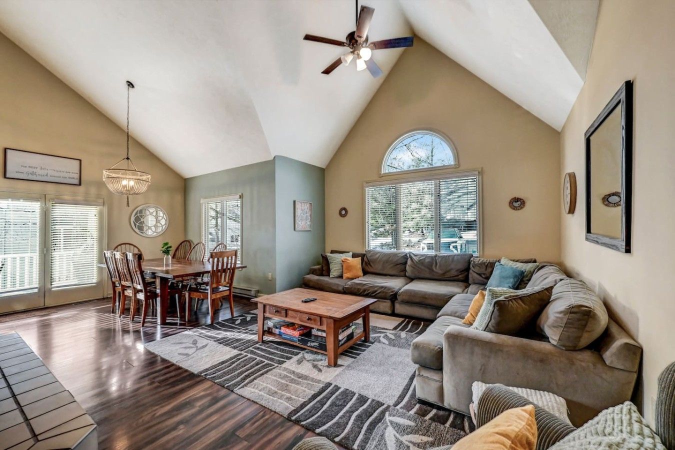 A spacious living room with a high ceiling, a dining area, and a large window providing natural light.