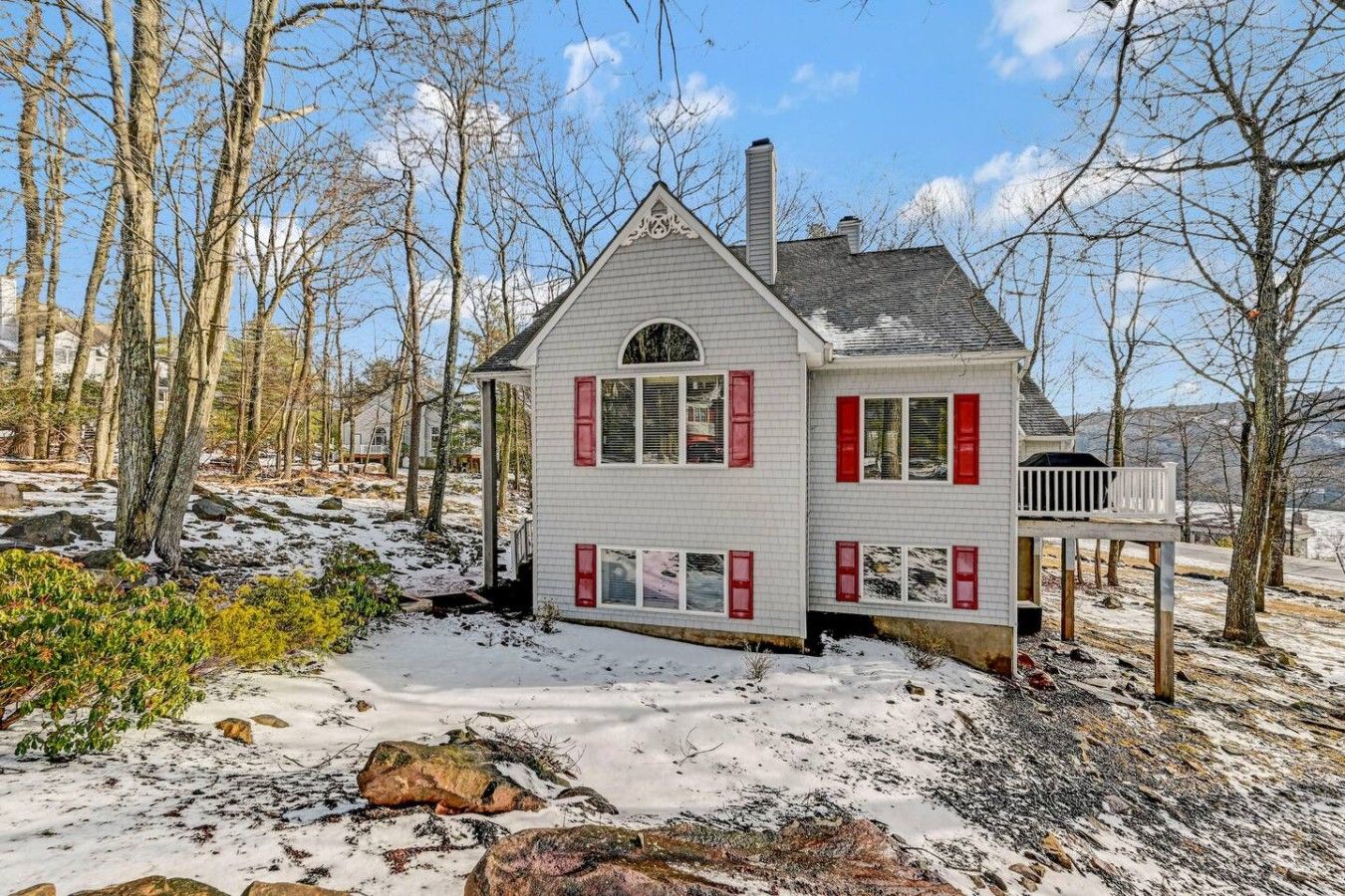 A two-story house with a gabled roof, red shutters, and a chimney.