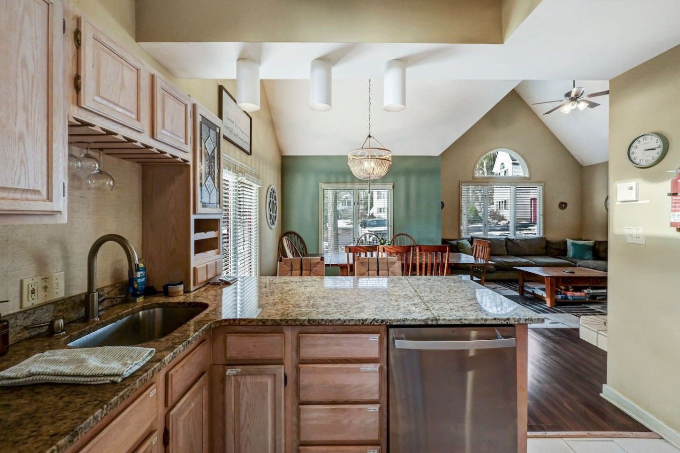 A kitchen with a central island, wooden cabinets, and a dining area with chairs and a table.