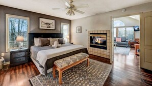 A bedroom with a large bed, a fireplace, a television, and a view of the outdoors. - Walk 2 Ski: Groups, Kids, Spacious & Well-Stocked (Lake Harmony)