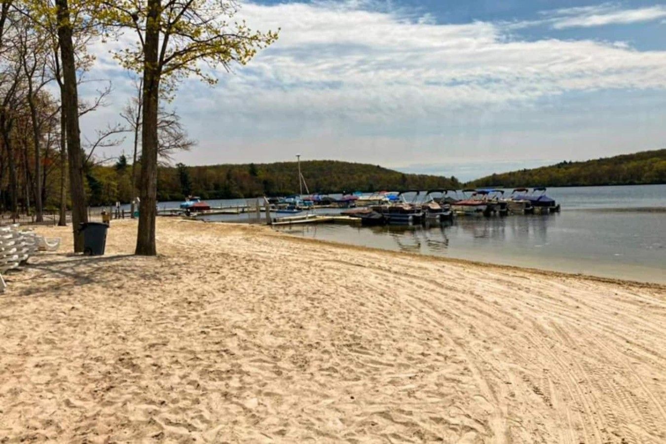 Een zandstrand met boten in het water, bomen en een heldere lucht.