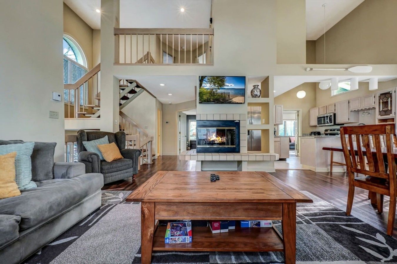 A spacious living area with a fireplace, a dining table, and a kitchen in the background.