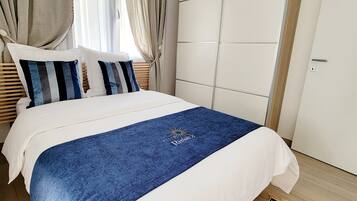 Ein Schlafzimmer mit einem Bett, Vorhängen, einem Kleiderschrank und einem gemusterten Teppich.