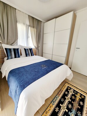 Ein Schlafzimmer mit einem Bett, Vorhängen, einem Kleiderschrank und einem gemusterten Teppich.