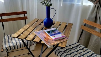 Een houten tafel met een blauwe vaas en een boek, omringd door gestreepte stoelen.