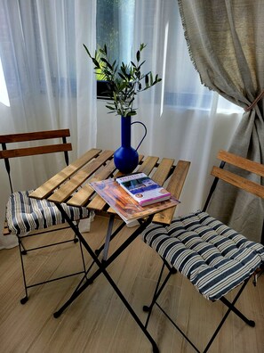 A wooden table with a blue vase and a book, flanked by striped chairs. - Spacious, fully equipped 2-room apartment in a quiet neighborhood (Saint-Paul-de-Vence)