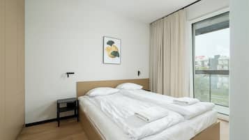 Un dormitorio moderno con una cama grande, una mesita de noche, una lámpara de pared y una ventana con cortinas.
