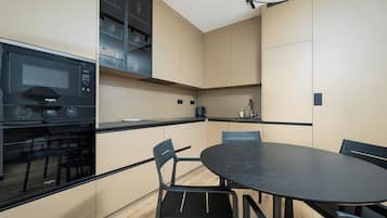 Una cocina compacta con microondas integrado, estufa y comedor con mesa redonda y sillas.