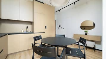 Une cuisine moderne avec une table à manger ronde et des chaises, un petit évier et un miroir rond accroché au mur.