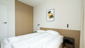Ein Schlafzimmer mit einem Bett, einem Nachttisch, einem Kleiderschrank und einem an der Wand hängenden Bild.
