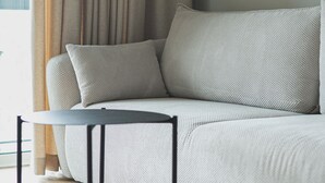 Ein modernes Wohnzimmer mit einem grauen Sofa, einem kleinen schwarzen Tisch und Holzboden.