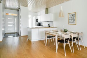 A modern kitchen with white cabinets, a dining table set for four, and a hanging pendant light. - Santa`s Gateway Home, Sauna By Lapland Host (Rovaniemi)