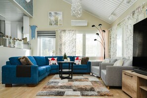 A modern living room with a blue sectional sofa, a grey sofa, a TV, and a fireplace.