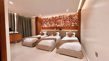 Ein Hotelzimmer mit drei Betten, einem Schreibtisch und einer Wand mit Muster.