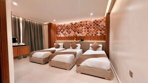 Une chambre d'hôtel avec trois lits, un bureau et un mur décoré de motifs.