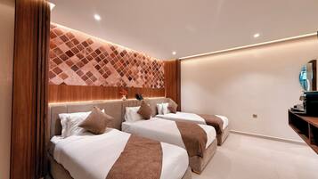 A hotel room with two beds, a wooden headboard, a wall-mounted phone, and a small table with a lamp.