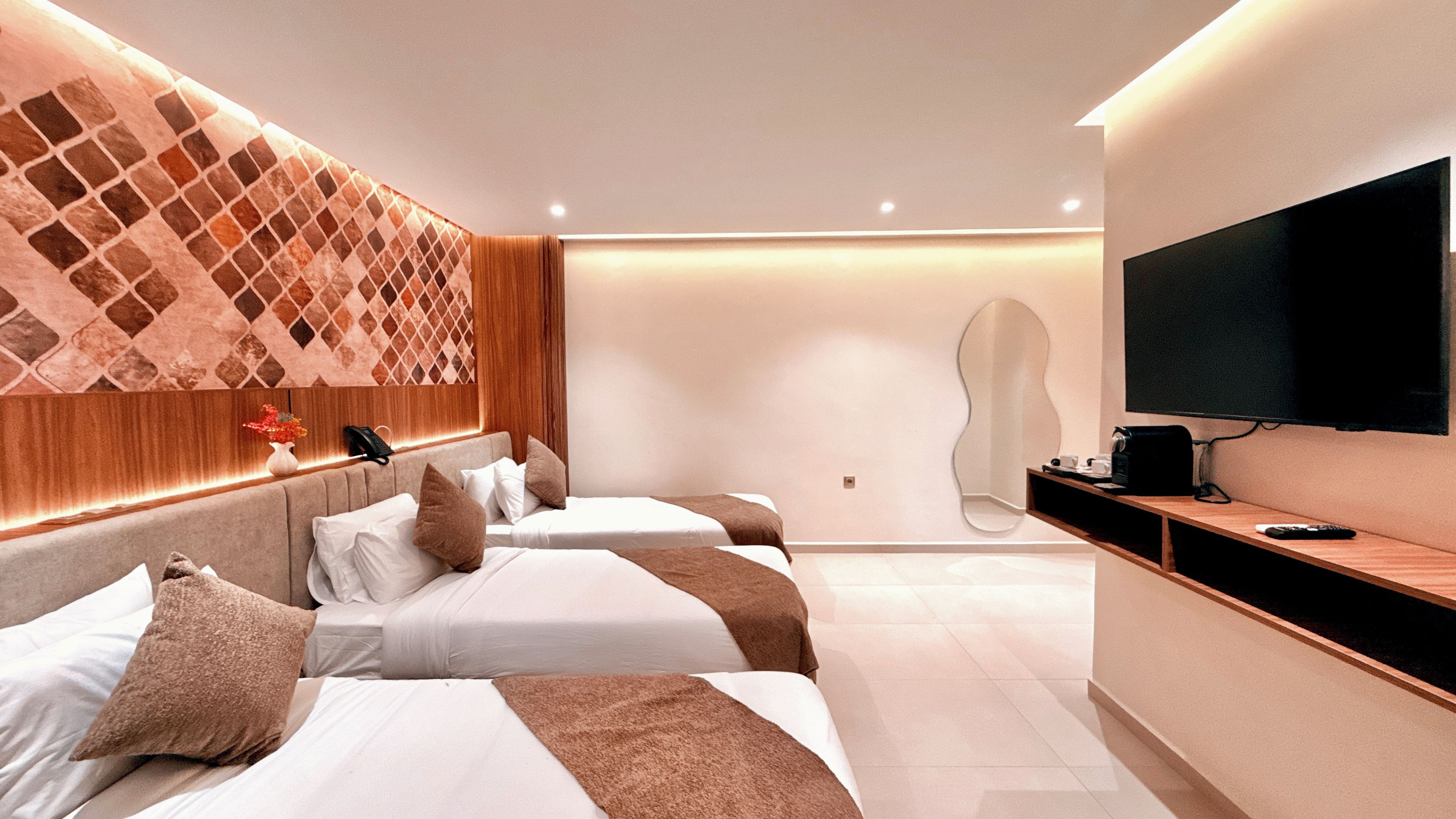 Une chambre d’hôtel avec deux lits, une télévision, un miroir et une console en bois.