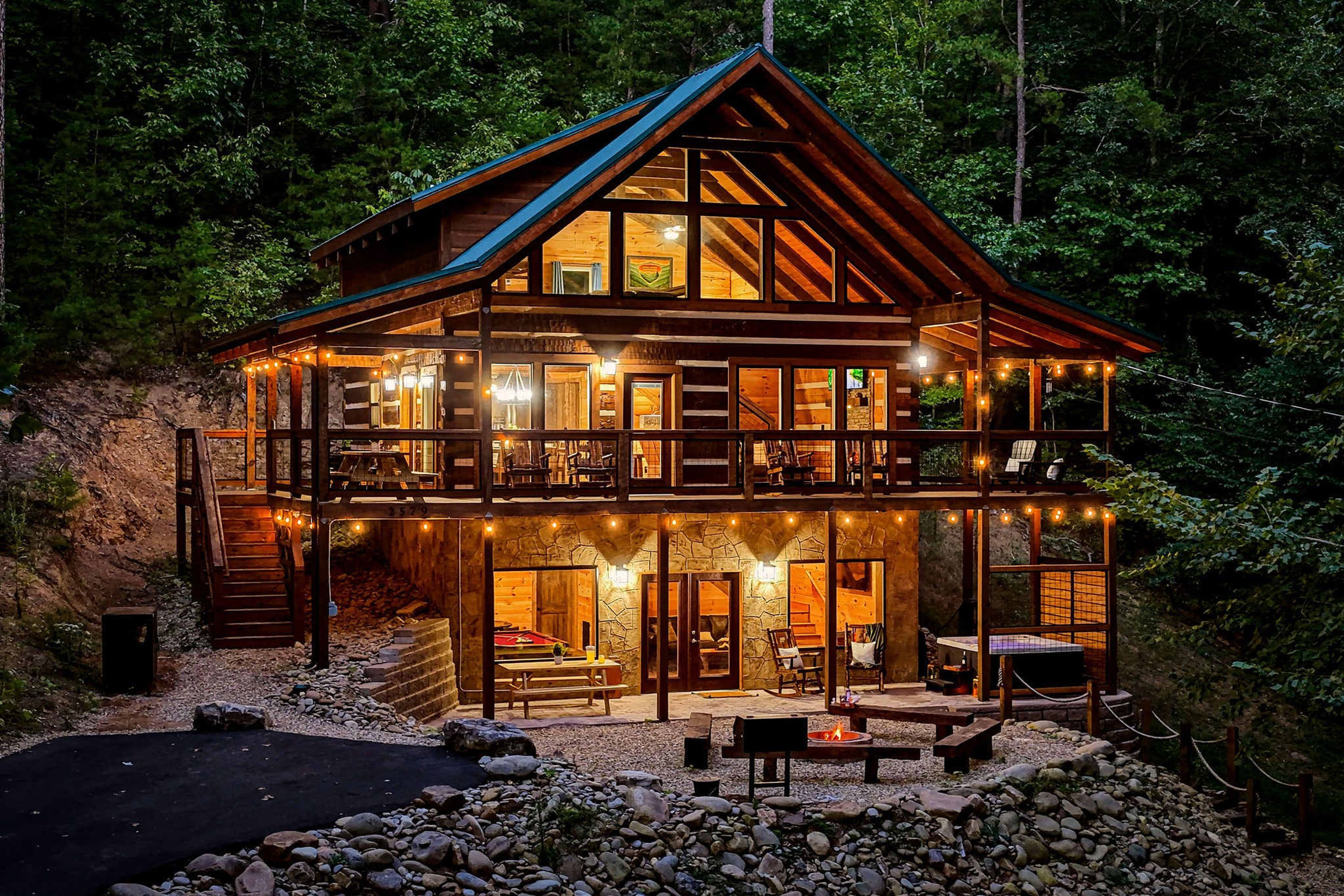 Eine zweistöckige Holzhütte mit Balkon, Steinmauern und Feuerstelle.