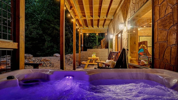 An outdoor hot tub area with a stone wall and wooden pergola. - Black Bear Ln in Sevierville (Sevierville)