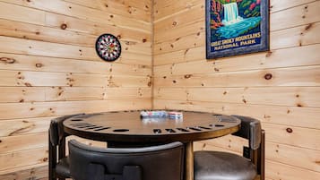 Ein Holzinnenraum mit Dartscheibe, einem Poster vom Great Smoky Mountains National Park und einem runden Tisch mit Stühlen.
