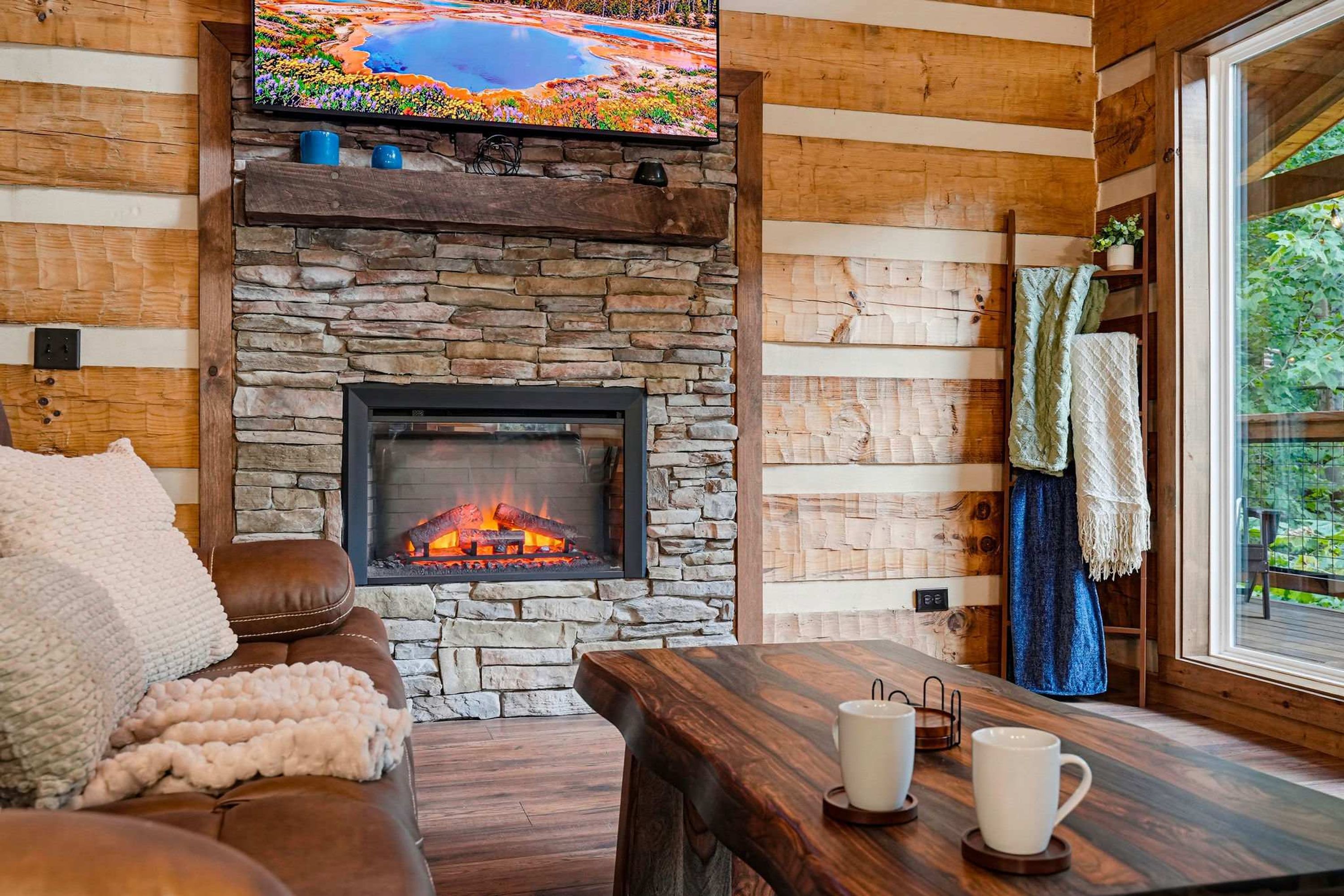 Una sala de estar acogedora con chimenea de piedra, paredes de madera, un sofá cómodo y una mesita de centro.