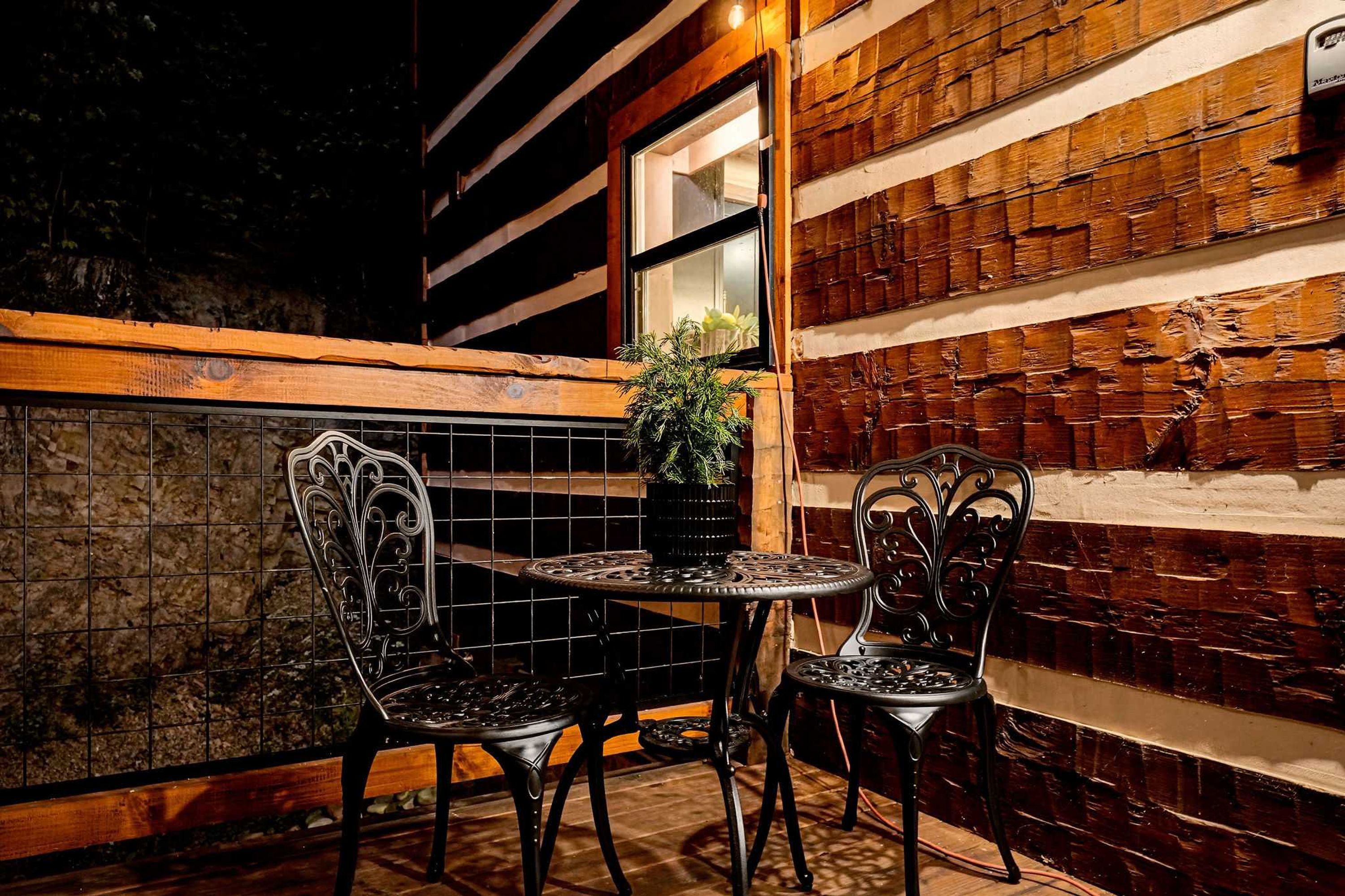 Un espace extérieur aménagé avec deux chaises et une table, un pot de fleurs et un mur en briques.