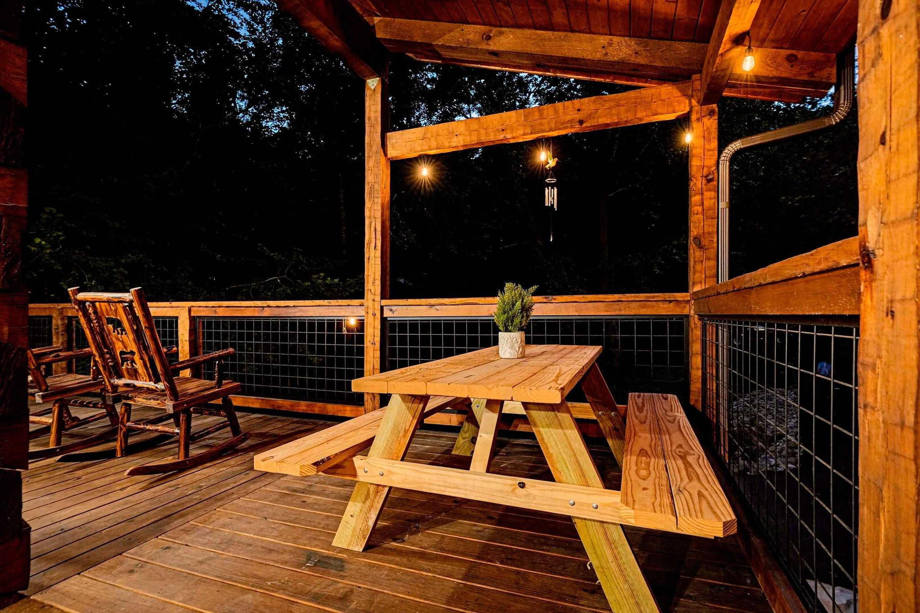 A wooden deck with a picnic table and chairs, surrounded by a wooden railing.