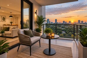 A modern living room with a sofa, armchair, and a table with candles, overlooking a city skyline at sunset. - Lovely 1-bedroom apartment with AC in charming Chimbli (Chimbli)
