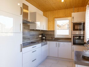 Eine moderne Küche mit weißen Schränken, Edelstahlgeräten und einem Fenster, das für natürliches Licht sorgt.