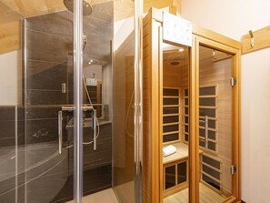 A sauna room with a glass door, a shower area with a glass enclosure, and a wooden sauna structure. - One-bedroom Cabin (Sankt Georgen am Kreischberg)