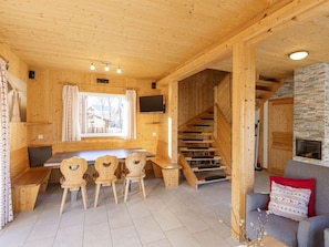 Ein Holzinnenraum mit Essbereich, einer Treppe und einem Kamin aus Stein.
