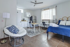 A compact hotel room with a bed, a desk, a chair, a kitchenette, and a ceiling fan. - Great Walkable Location! Tucson Studio Stay (Tucson)