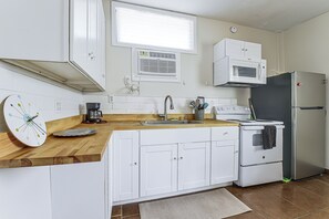 A compact kitchen with white cabinets, a microwave, a refrigerator, a coffee maker, and a clock on the counter. - Great Walkable Location! Tucson Studio Stay (Tucson)