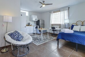A compact hotel room with a bed, a desk, a chair, a kitchenette, and a ceiling fan. - Great Walkable Location! Tucson Studio Stay (Tucson)