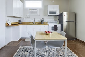 A compact kitchen with white cabinetry, a wooden countertop, a stainless steel refrigerator, and a dining table with chairs. - Great Walkable Location! Tucson Studio Stay (Tucson)