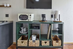 Eine Küchenarbeitsfläche mit Kaffeemaschine, Toaster und einem darüber angebrachten Fernseher.