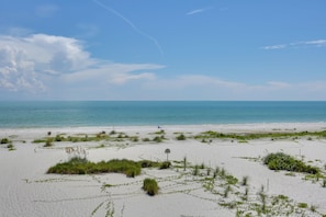 A beach with sand, sparse vegetation, and a clear sky. - Access to Pool & Sanibel Beach: Resort-style Condo (Sanibel)
