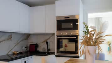 Een moderne keuken met witte kasten, een houten eettafel en een potplant.